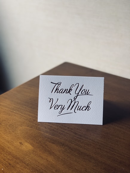 a thank you card sitting on a wooden table