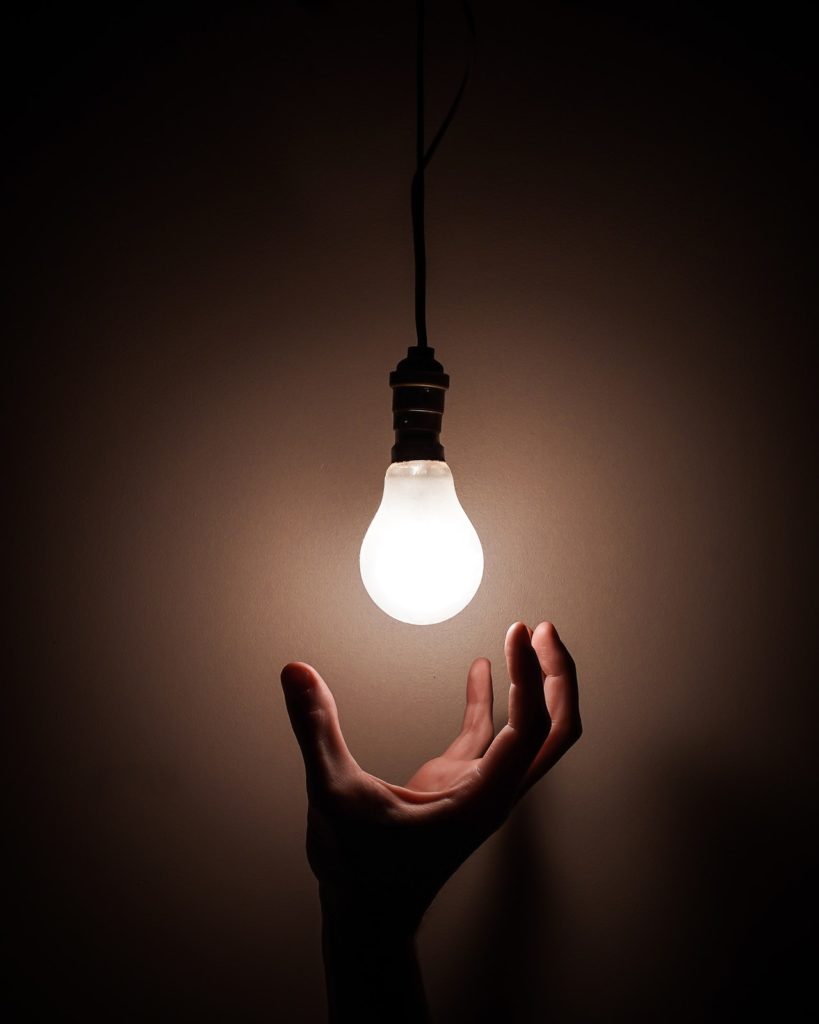 a person's hand reaching up to grab a light bulb
