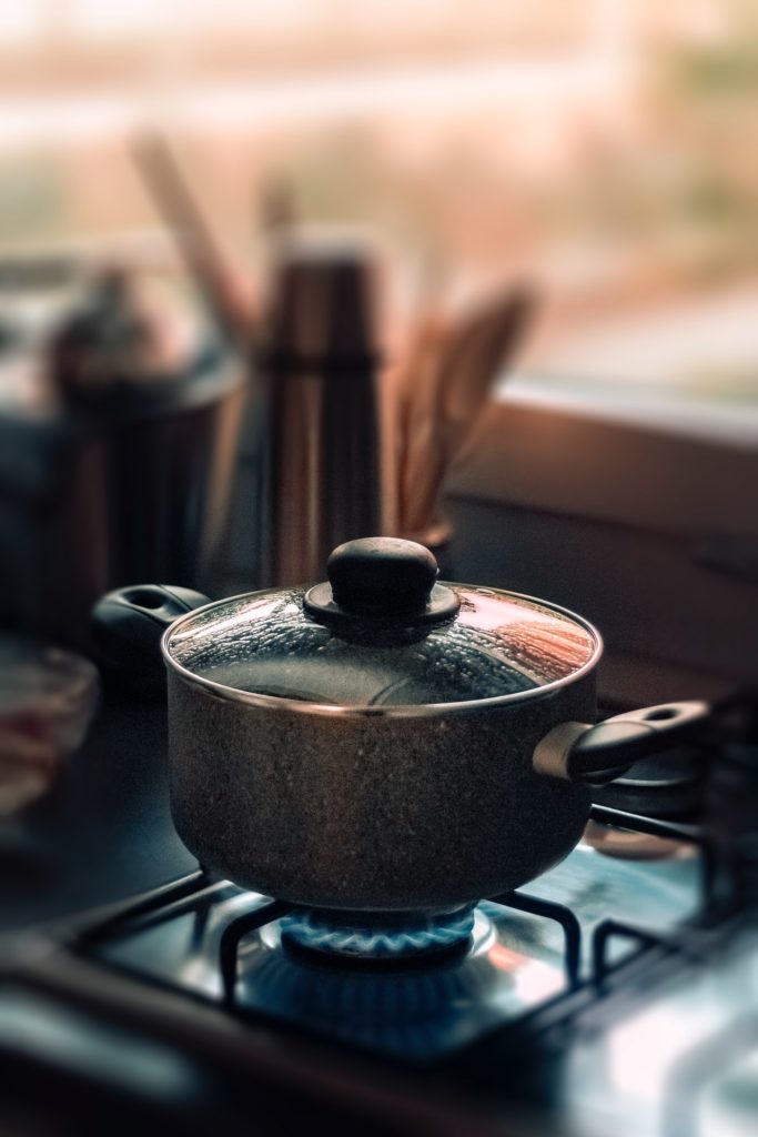 a pot boiling water on a burner with a blue hot flame