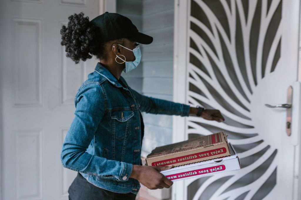 woman in a blue denim jacket delivering food by Rodnae